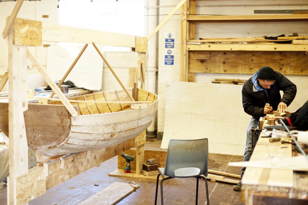 A handcrafted wooden rowing boat is nearing completion. Boat Building Academy, Lyme Regis