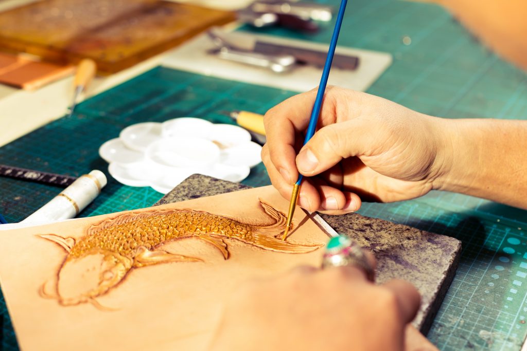 Chinese traditional leatherworker painting fish pattern on the leather