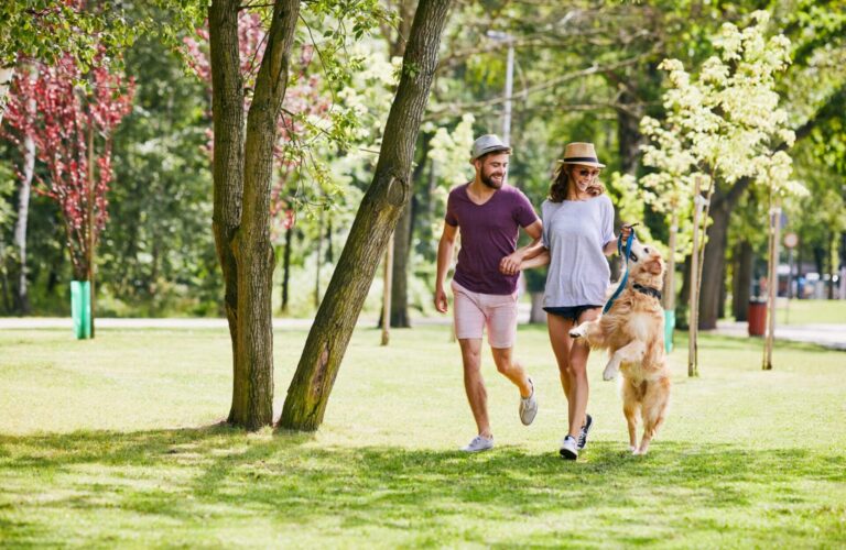 Young Couple Running And Playing With Their Dog Outdoors In The Morning Young couple running and playing with their dog outdoors in the morning