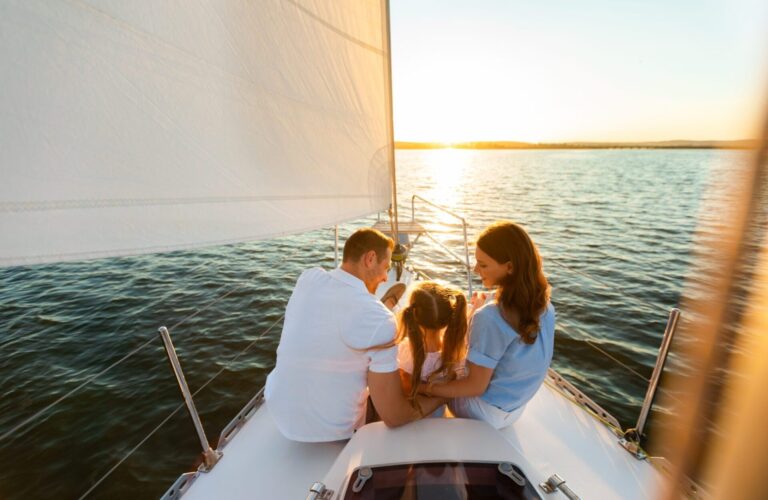 Family Yacht Sailing, Parents And Daughter Sitting On Deck, Back View Family Yacht Sailing. Parents And Little Daughter Sitting Together On Sailboat Deck Hugging Enjoying Sea Trip. Back View, Free Space